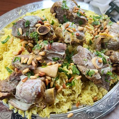 منسف بلحم الغنم على فراش من الأرز، مسقي بصلصة اللبن