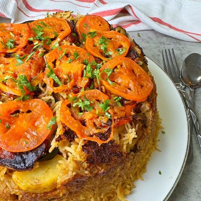 طبق مقلوبة مقلوب على الصحن، مع شرائح طماطم مشوية وبقدونس مفروم فوق الأرز
